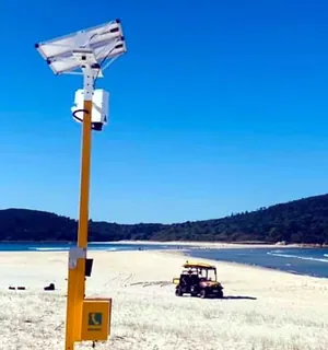 Close view of a yellow Emergency Response Beacon pole on Fingal Beach with its solar panel and call unit