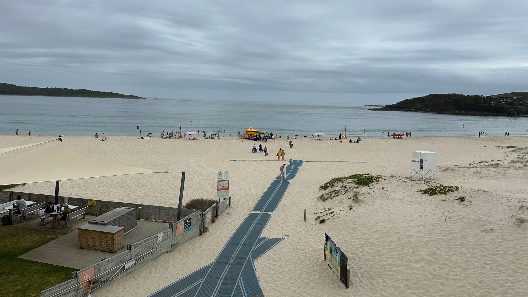 Wide view of Fingal Beach showing the patrol tent, red and yellow flags, beach access matting and the patrolled swimming area