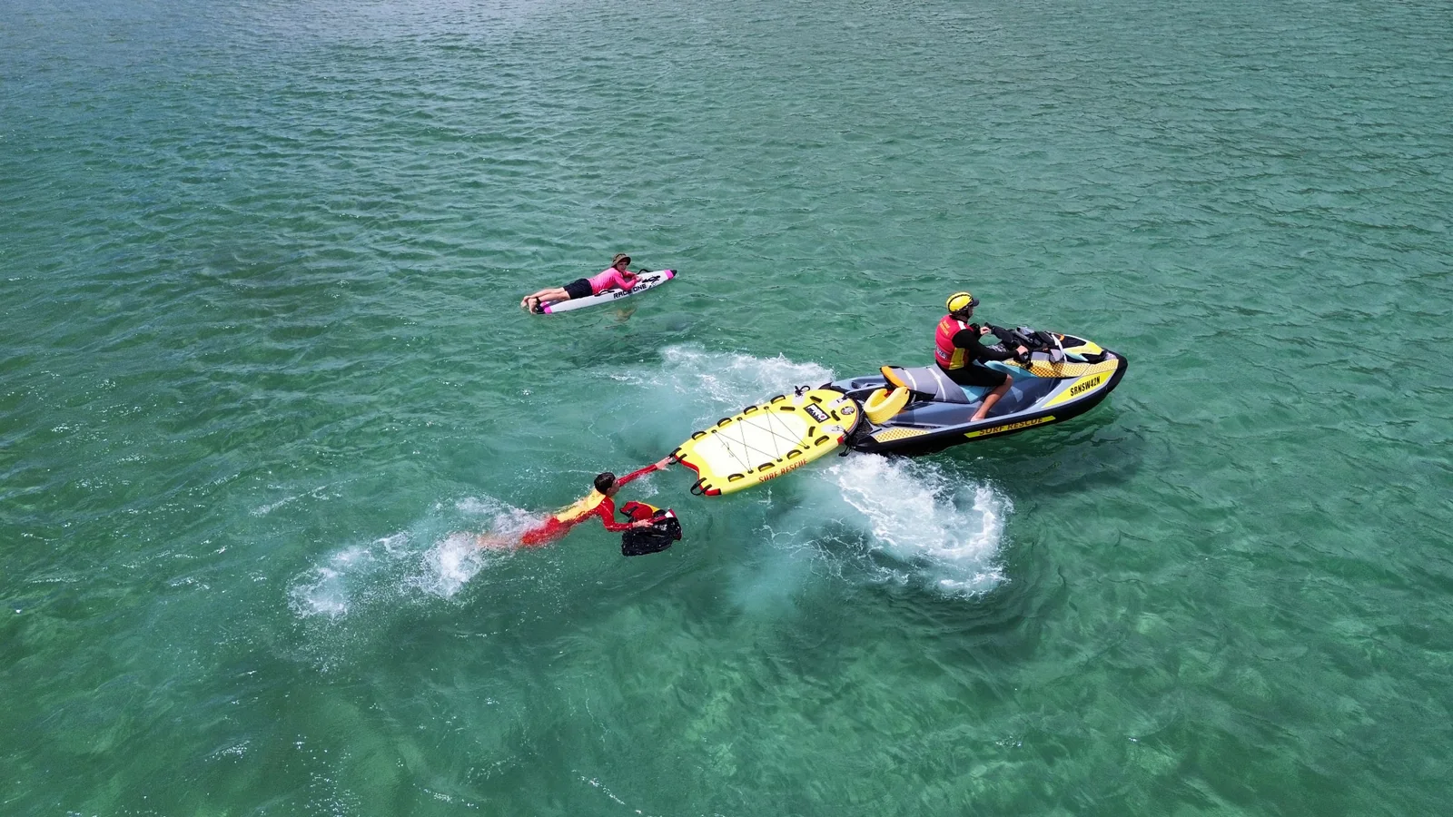Surf rescue personal water craft and rescue sled operating with people in the water at Fingal Beach